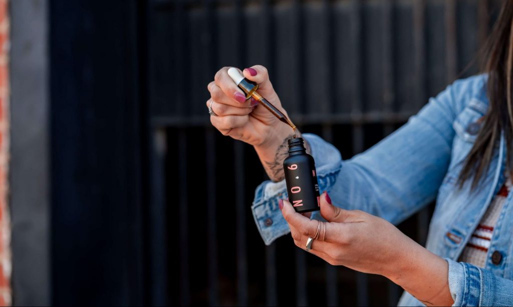 woman holding cosmetic drop bottle