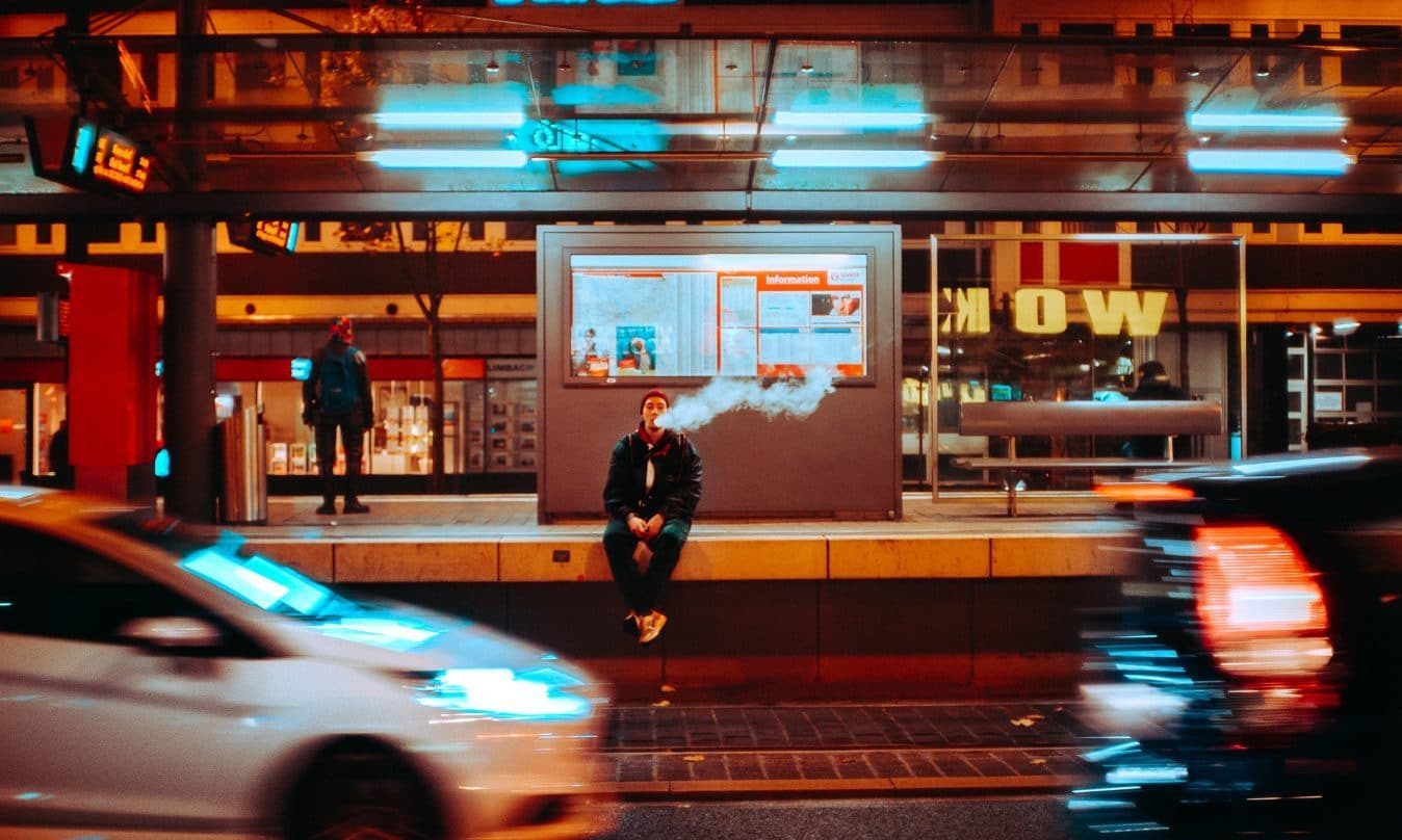 time lapse photography of man sitting on ledge smoking during night time