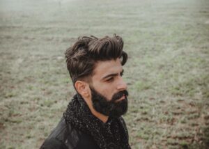 man in black leather jacket standing near body of water during daytime