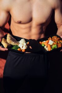 topless man in black shorts holding cooked food