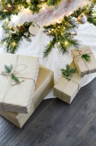 Beautifully wrapped Christmas gifts under a festive tree with glowing lights.